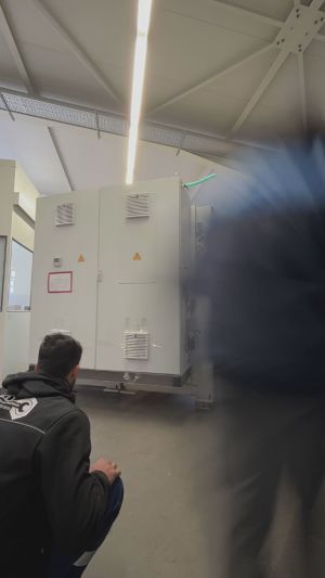 Arbeiter bei der Inspektion eines industriellen Schaltschranks in einer Fabrikumgebung