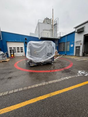 Plastic-Covered Equipment Outside a Factory With Blue and Grey Warehouse