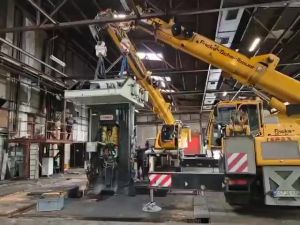 Industriekran hebt schwere Maschinen in einer ger&auml;umigen Fabrikhalle
