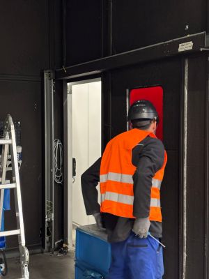 Worker in High-Visibility Vest Entering Industrial Facility Through Doorway