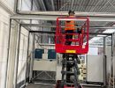 Technician Using a Scissor Lift for Pipe Installation in Industrial Facility