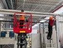 Workers Utilizing Elevated Platforms in a Spacious Industrial Facility