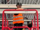Construction Worker in Safety Gear on Elevated Platform in Warehouse