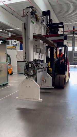 Worker Operating Forklift to Move Machinery in Industrial Facility