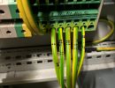 Gelbe und gr&uuml;ne elektrische Dr&auml;hte, die an die Klemmleiste in der Schalttafel angeschlossen sind