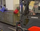 Industriearbeiter, der einen Gabelstapler bedient, um schwere Ausr&uuml;stung im Lager zu transportieren