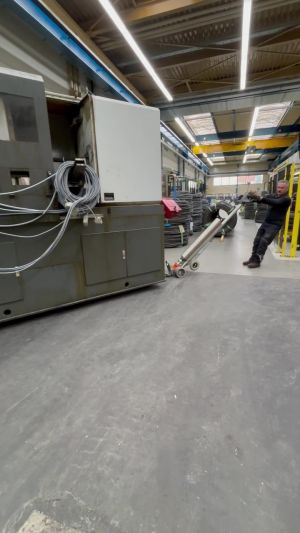 Industriearbeiter beim Man&ouml;vrieren von Ger&auml;ten in einer hellen Fabrikumgebung