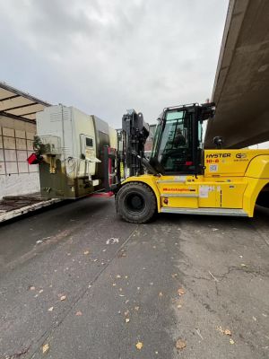 Gelber Gabelstapler, der Ausr&uuml;stung auf eine LKW-Plattform im Freien transportiert