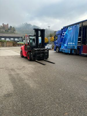 Roter Gabelstapler und offener Lastwagen in einer industriellen Au&szlig;enumgebung