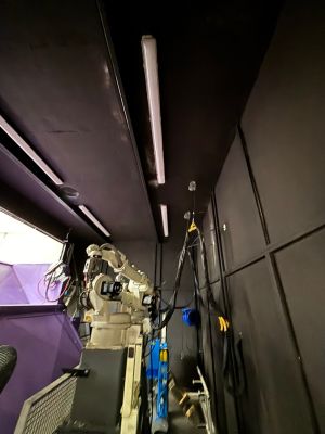 Industrieroboterarm in einer Werkstatt mit sichtbaren technischen Komponenten und Verkabelung