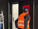 Arbeiter in Warnweste betritt Industrieanlage durch T&uuml;r&ouml;ffnung