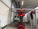 Bauarbeiter, die eine Scherenhebeb&uuml;hne und eine Leiter in einer industriellen Umgebung benutzen