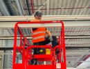 Arbeiter auf einer Hebeb&uuml;hne bei Wartungsarbeiten im Inneren eines Industriegeb&auml;udes