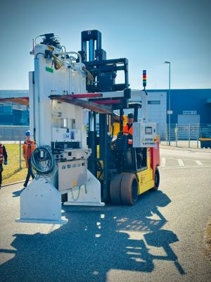 Gabelstapler bei der Handhabung von Industriemaschinen im Freien an einem hellen, sonnigen Tag