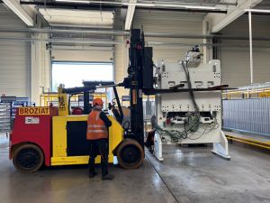 Arbeiter, der einen Gabelstapler in einem Industrielager bedient und gro&szlig;e Maschinen hebt